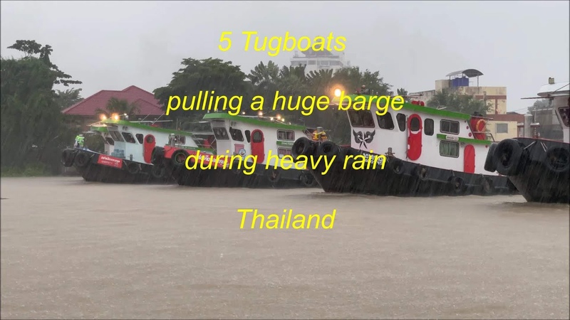 5 Tugboats pulling a huge barge during heavy rain in